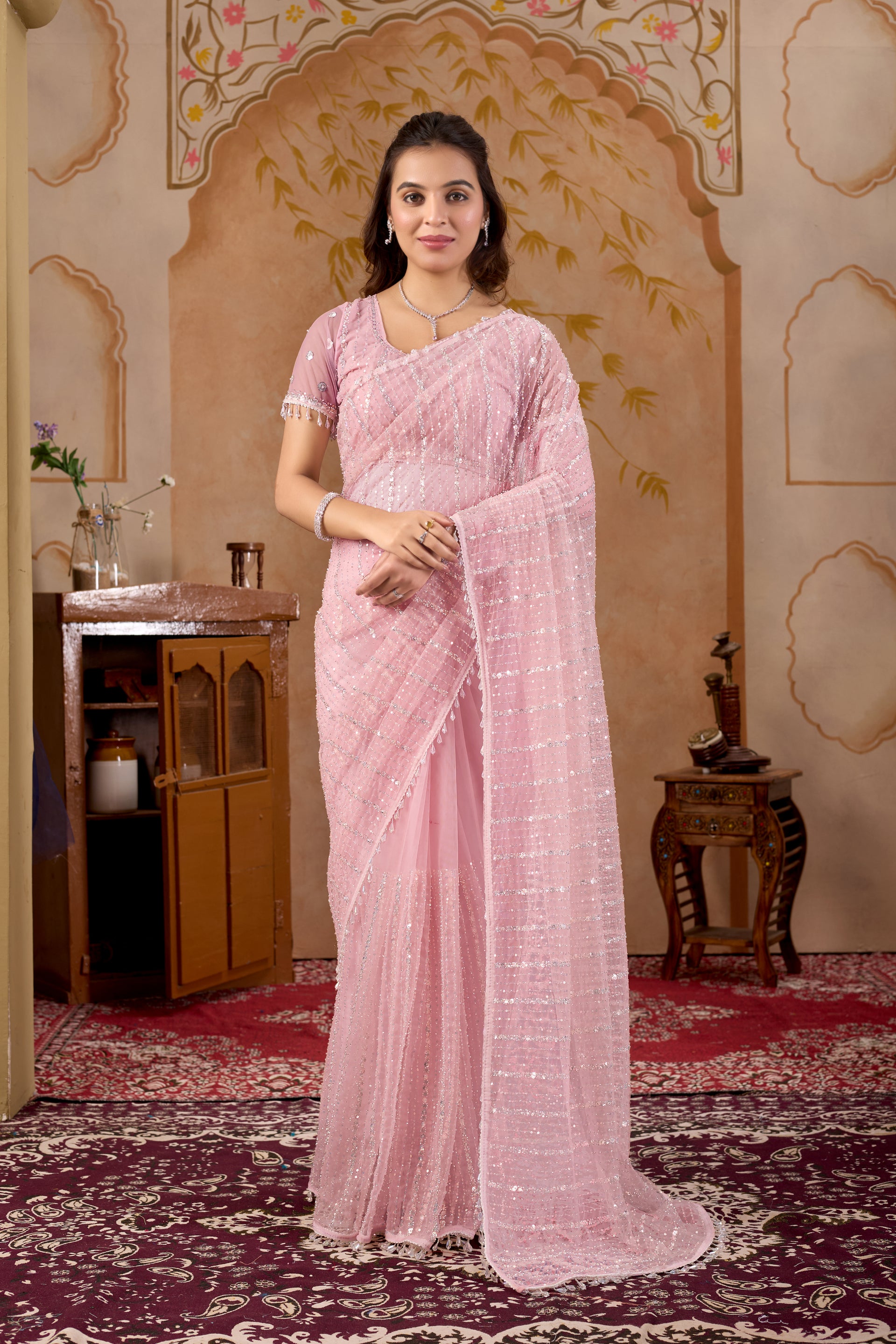 Pink net saree with intricate handwork and unstitched blouse from Kanyaari, showcasing delicate embroidery and sheer fabric.